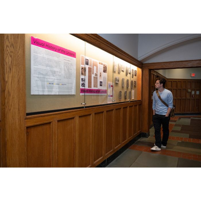 male presenting person looking at artwork in glass display case
