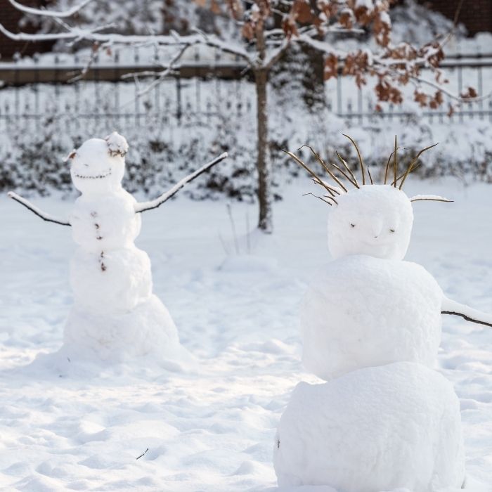 two snowmen on a snowcovered lawn
